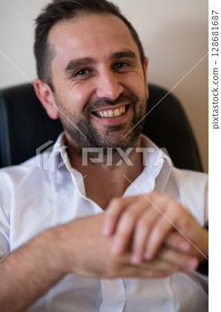 A businessman talking on his smartphone while seated in an office, showcasing his professional demeanor and active communication. 128681687