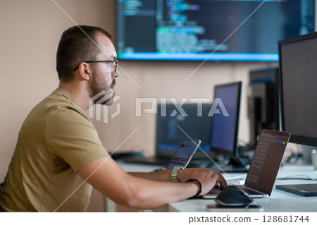 A programmer diligently testing smartphone applications while sitting in their office. 128681744