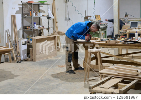 Close Up of Worker Carefully Cutting and Planing Wooden Pieces for Furniture in Wood Industry Close Up of Worker Carefully Cutting and Planing Wooden Pieces for Furniture in Wood Industry 128681967