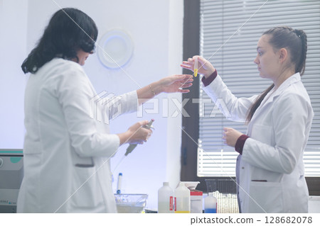 Two scientists holding test tubes with yellow liquid 128682078