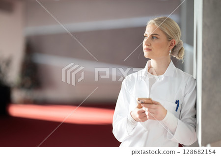 Young female doctor using smartphone during break 128682154