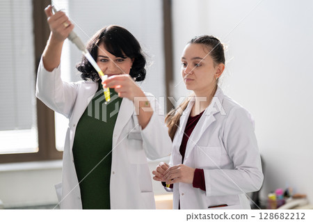 Two scientists holding test tubes with yellow liquid 128682212