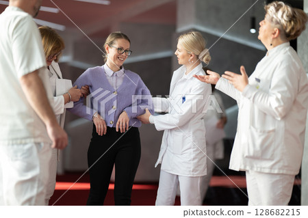Medical team helping patient with walking therapy Medical team helping patient with walking therapy 128682215