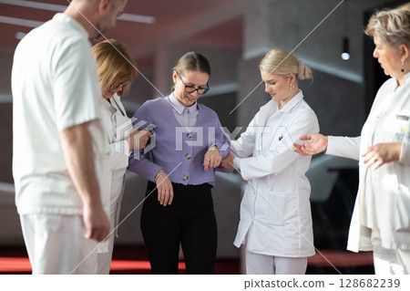 Medical team helping patient with walking therapy 128682239