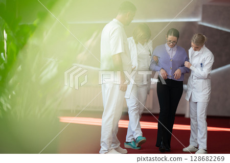 Medical team helping patient with walking therapy 128682269