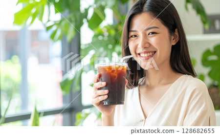 Young female business person drinking iced coffee 128682655