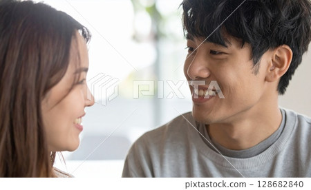 Smiling couple in their 20s looking at each other 128682840