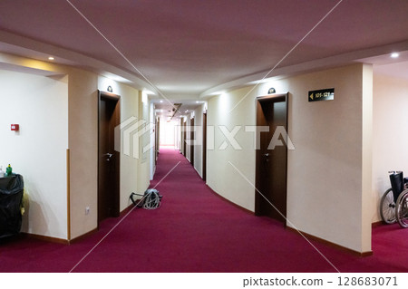 A modern, spacious hallway in a rehabilitation clinic, featuring clean lines, bright lighting, and well-designed patient rooms that promote healing and comfort 128683071