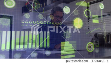Analyzing senior data analyst reviewing documents and laptop in office, holographic data overlays Analyzing senior data analyst reviewing documents and laptop in office, holographic data overlays 128683104