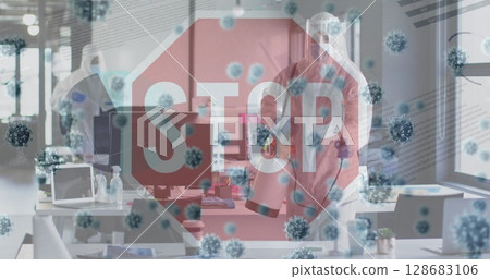 Decontaminating workers wearing hazmat suits spraying disinfectant on monitors in office, STOP sign 128683106