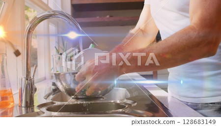 Image of light spots and trails over caucasian man washing vegetables in kitchen 128683149