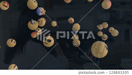 Image of falling emojis over women using laptop 128683205