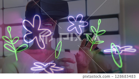 Image of flower neon shapes over caucasian woman using vr headset 128683483