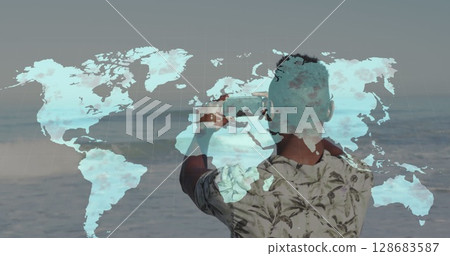 World map over rear view of african amerian man taking pictures from his smartphone at the beach 128683587