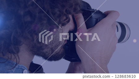 Spot of light against african american male photographer clicking pictures with digital camera 128683610