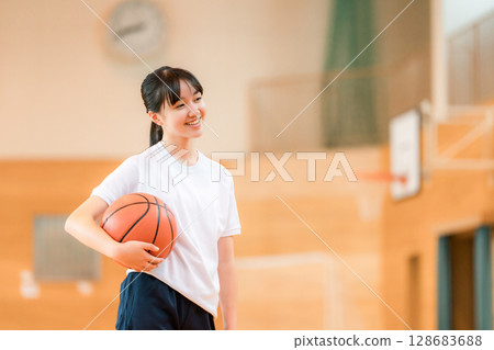Female junior high school students and high school students wearing gym clothes holding basketballs in a gymnasium 128683688