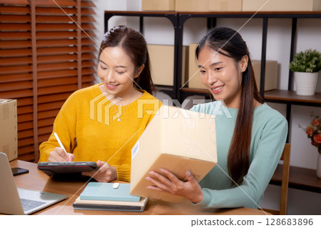 Two young asian woman working while planning online business and checking order. Two young asian woman working while planning online business and checking order. 128683896