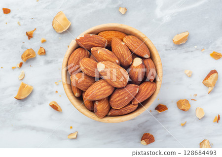 Almond in wooden bowl with broken almonds on marble table background 128684493