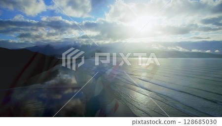 Image of landscape with ocean over caucasian siblings with american flag at beach 128685030