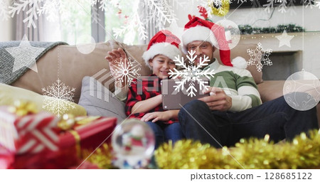 Image of snow falling at chrsitmas over happy caucasian father with son having image call 128685122