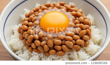 Bowl of white rice topped with fermented soybeans and a raw egg yolk. 128686388