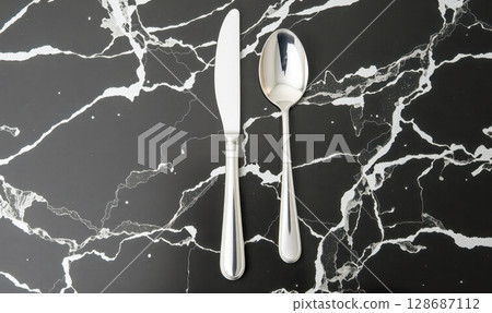 Luxury silver knife and spoon on black marble background, elegant modern cutlery set for fine dining restaurant or exclusive event, top view with copy space Luxury silver knife and spoon on black marble background, elegant modern cutlery set for fine dining restaurant or exclusive event, top view with copy space 128687112