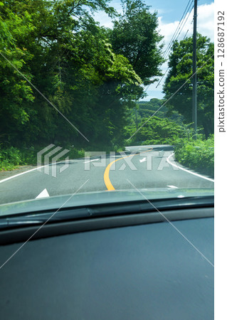 Curving road with a yellow center line and white arrows 128687192