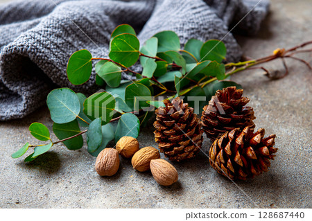Green Leaves and Pine Cones on Rustic Winter-Themed Background 128687440