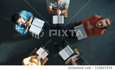 Top down view of prayers reading bible while making folded hands. Symposium. 128687478