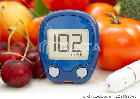 Asian hand holding digital glucose monitor measure with vegetable and fruit healthy food. 128688565