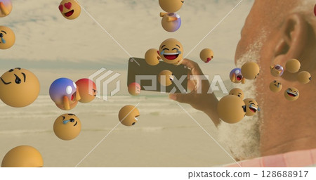 Image of media icons over senior african american man taking selfie on sunny beach Image of media icons over senior african american man taking selfie on sunny beach 128688917