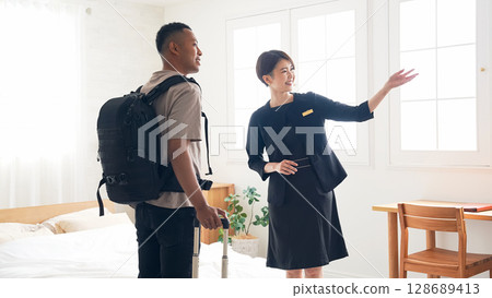 飯店女工作人員帶一名黑人男遊客參觀房間 128689413