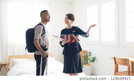 Female hotel staff showing a black male tourist to his room 128689421