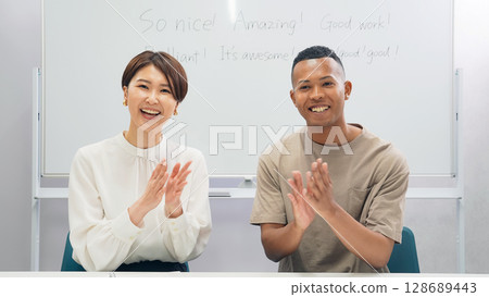 Black man and Japanese woman clapping in classroom Black man and Japanese woman clapping in classroom 128689443