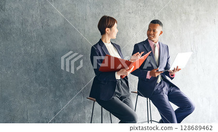一位黑人男性商人和一位日本女性工作人員在一間時尚的房間裡交談 128689462