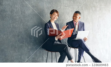 一位黑人男性商人和一位日本女性工作人員在一間時尚的房間裡交談 128689463