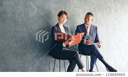 一位黑人男性商人和一位日本女性工作人員在一間時尚的房間裡交談 128689464