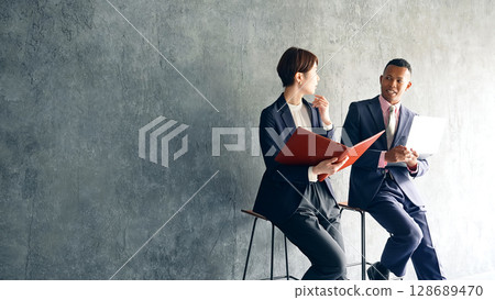A black male businessman and a Japanese female staff member having a conversation in a stylish room A black male businessman and a Japanese female staff member having a conversation in a stylish room 128689470