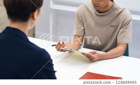 A black man and a Japanese female staff member having an interview 128689493