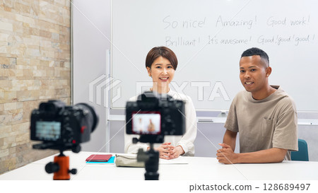 A black man and a Japanese woman filming a video 128689497