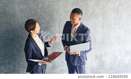 A black male businessman and a Japanese female staff member having a conversation in a stylish room 128689500