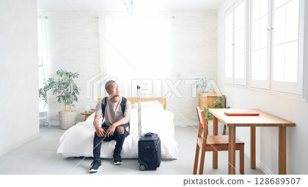 Black male traveler looking at smartphone in hotel room Black male traveler looking at smartphone in hotel room 128689507