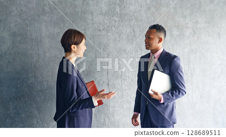 一位黑人男性商人和一位日本女性工作人員在一間時尚的房間裡交談 128689511