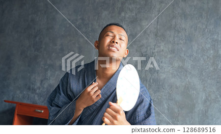 A foreign man wearing a yukata and fanning himself with a fan A foreign man wearing a yukata and fanning himself with a fan 128689516