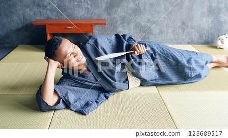 A foreign man wearing a yukata lying on a tatami mat to cool off A foreign man wearing a yukata lying on a tatami mat to cool off 128689517