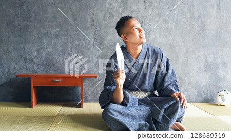 一名身穿浴衣的黑人男子在榻榻米上休息 128689519