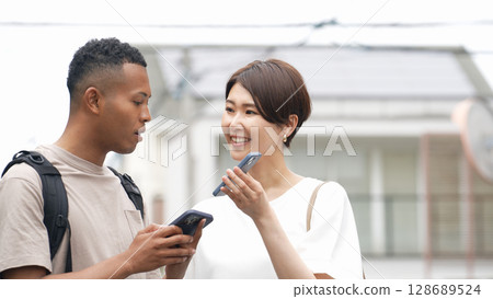 一名日本女性正在使用智慧型手機翻譯應用程式與一名黑人男子交談 128689524