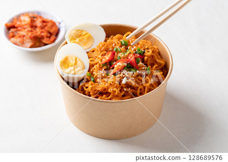 Spicy Korean dried instant noodles with boiled egg, sliced scallions, sesame seed and fresh chili  128689576