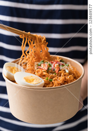 Spicy Korean dried instant noodles with boiled egg, sliced scallions, sesame seed and fresh chili  128689577