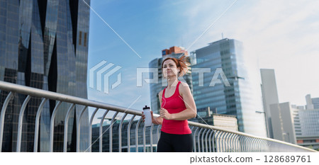 sporty woman running across a city bridge during her morning workout. sporty woman running across a city bridge during her morning workout. 128689761